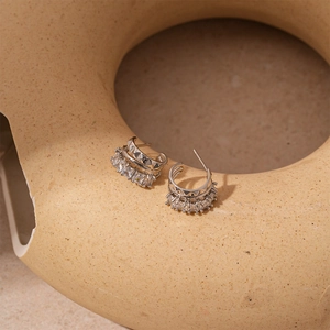 Detailed view of silver C-shaped earrings with zircon inlay and geometric texture