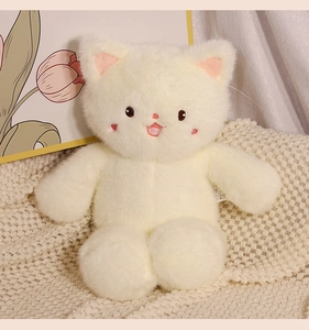 Close-up of a white plush cat toy with soft fur and pink heart embroidery