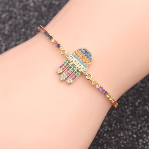 Détail du bracelet main de Fatma dorée avec zircons colorés et texte 'mama' porté