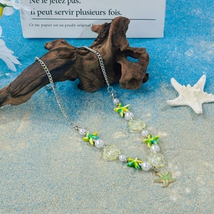 Beaded shell necklace with colorful starfish pendants and pearls on a beach setting