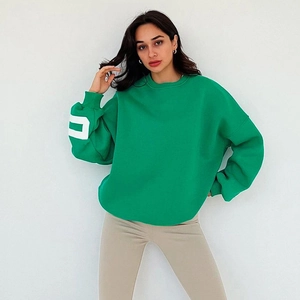 Détail de l'imprimé lettres blanches sur le poignet d'un sweat-shirt vert oversize