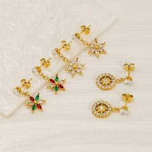Titanium steel gold flower earrings with zircon inlays on white marble and silk background