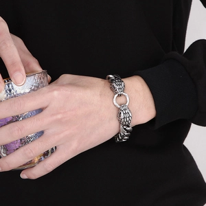 Macro detail of retro steel Cuban chain bracelet with dual snake head engraving