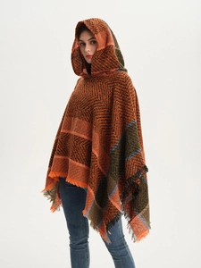 Detail of herringbone knit hooded poncho with orange-green color block and tassels