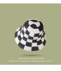 Detail of black and white checkered straw bucket hat with natural woven texture