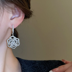 Detail of silver camellia drop earring featuring layered hollow petals and pavé zircon