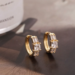 Macro shot of gold hoop earrings with inlaid square and rectangular clear zircons