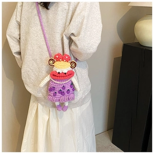 Detail of a handmade purple crochet crossbody bag featuring a cartoon character design