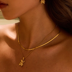 Close-up of golden stainless steel double-layered necklace and bear pendant on model