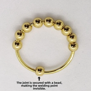 Detail view of seamless hidden joint with gold rotating beads on stainless steel ring