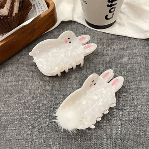 Schattige witte parelmoer konijn haarklemmen met pluche bal op een grijze stof