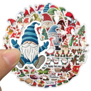 Hand holding a waterproof Christmas gnome sticker with various holiday designs in background