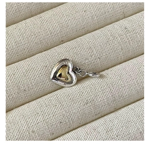 Macro shot of two-tone S925 silver and gold heart pendant on white fabric background