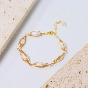 Detailed shot of handmade gold wire-wrapped bracelet with natural white pearls