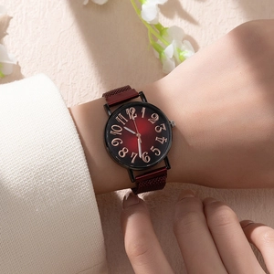 Détail d'une montre femme avec cadran dégradé rouge et bracelet magnétique au poignet