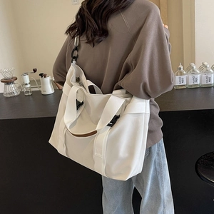 White canvas tote bag shown on model in a cozy cafe, casual large shoulder handbag style