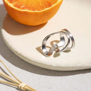 Artistic wavy texture stainless steel ring displayed on a minimalist ceramic plate