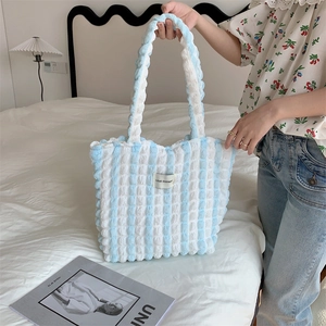 Blue and white striped bubble texture tote bag held against cozy home background