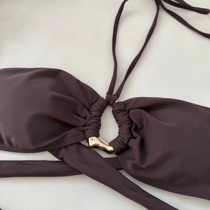 Close-up of brown bikini top featuring a gold metal ring and elegant pleated fabric