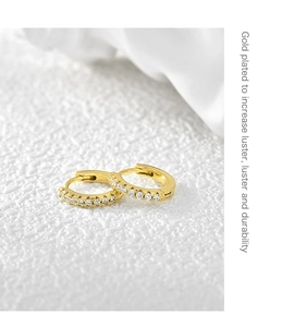 Macro view of gold plated hoop earrings featuring a single row of inlaid zircons