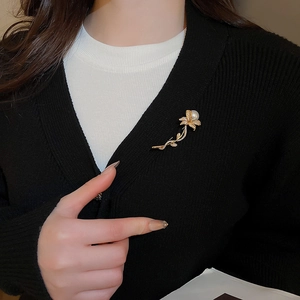 Detail of vintage zircon flower brooch with pearl on a black knitted cardigan