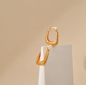 Chunky gold U-shaped hoop earrings with textured spring coil design in 18K gold plated brass