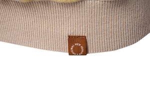 Detailed close-up of knit hem with brown woven label on men's beige polo shirt