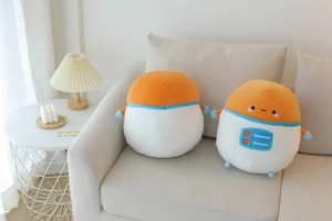 Detail view of two astronaut plush pillows with embroidery on a cozy white sofa