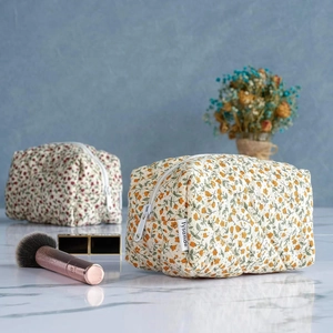 Detailed view of floral pattern makeup bag on marble surface with dried flower decor