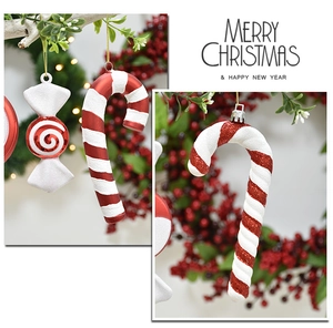 Close-up of red and white striped candy cane ornaments with glitter on Christmas pine branches