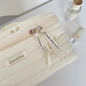 Detailed macro view of quilted makeup bag with double zippers and elegant ribbon