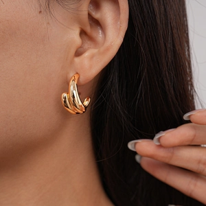 Detailed view of layered golden knot earrings on model highlighting metallic texture and size