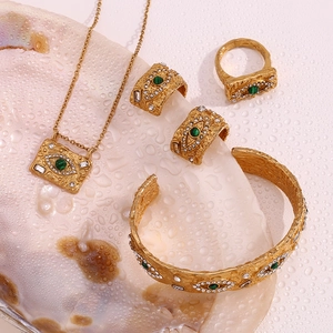 Detail of gold evil eye jewelry set with malachite and crystals on shell background