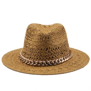 Macro detail of hand-woven straw fedora hat with elegant gold chain decoration