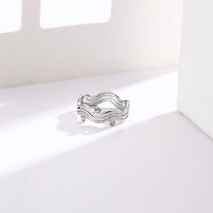 Macro shot of silver stainless steel ring with wavy texture and three clear gemstones
