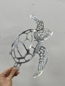 Detail of laser-cut turtle wall art with a brushed silver metal finish and hollow design