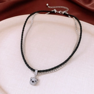Detail of double-layer necklace with crystal bear pendant on beige textured plate