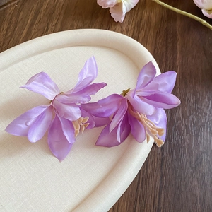 Close-up of purple fabric hibiscus flower hair clips on a textured jewelry tray