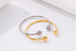 Close-up of minimalist gold and silver open bangles with polished spherical ends