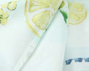 Macro detail of lemon print poplin fabric showing clean overlock stitching and texture