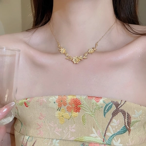 Detailed view of elegant gold floral and leaf pendant necklace worn on a model