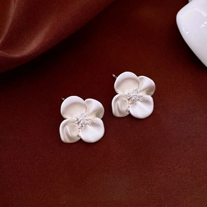Silver needle flower earrings with matte finish and zirconia stones on silk background