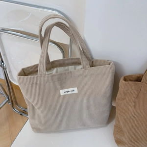 Detail of beige corduroy tote bag featuring a simple wish label and soft ribbed texture