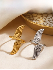 Detailed view of gold and silver angel wing open rings on beige velvet and golden tray