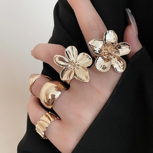 Detailed view of irregular gold flower rings and textured bands on a model hand