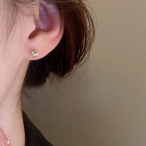 Close-up of elegant heart-cut crystal stud earring with gold plating on a model ear