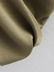 Macro view of army green twill fabric showing detailed texture on long sleeve jacket