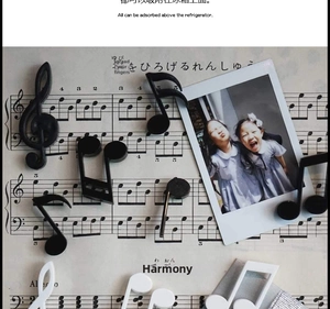 Close-up of musical note magnets and treble clef on a sheet music background