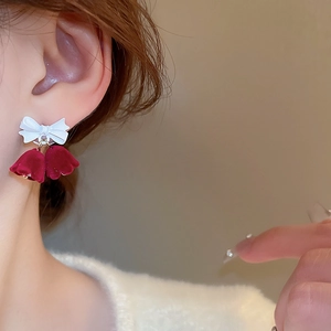 Detail of velvet red lily of the valley earrings with white bow on model's ear