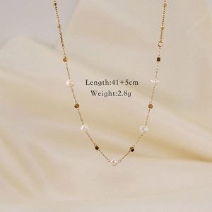 Detailed view of a gold pearl necklace featuring white shell charms on silk fabric